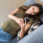 Woman laying on couch watching videos on her phone
