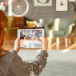 A woman uses a tablet to take images of a model home.