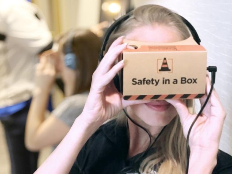 Young woman with headphones looking through virtual box with Safety In A Box logo
