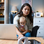 young mom working on laptop with baby in lap