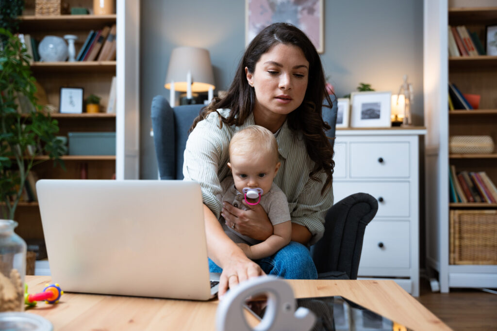 young mom working on laptop with baby in lap