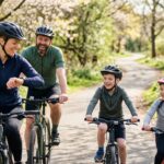 Happy family with two children riding bicycles on a sunny park trail during spring